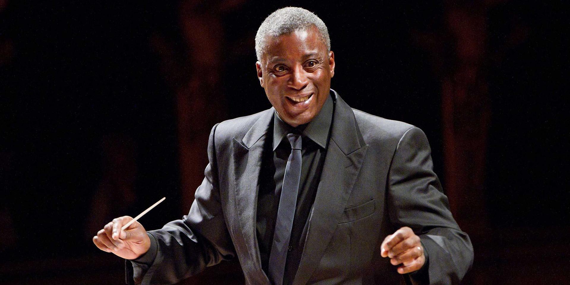 Wayne Marshall mentre dirige, con abito scuro su fondo nero